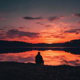 湖畔で夕日を眺める男性 湖畔で夕日を眺める男性の写真