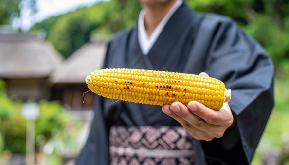 焼きとおもろこしを手に持つ浴衣姿の男性 焼きとおもろこしを手に持つ浴衣姿の男性の写真