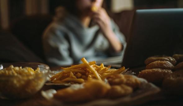 食事をしながらノートパソコンを操作する人の写真