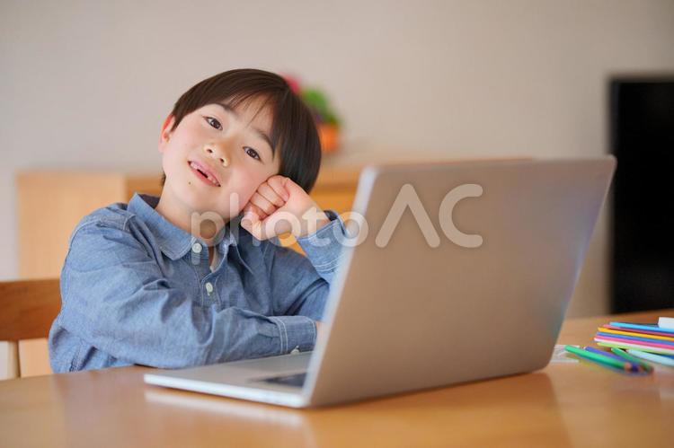 パソコンの横でポーズをする男の子 男の子,頬杖,ポーズの写真素材