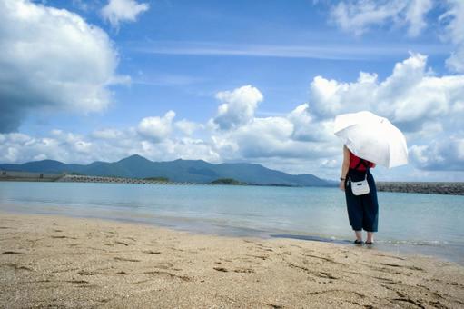 <素材>夏の海で一人空の雲を眺める女性 <素材>夏の海で一人空の雲を眺める女性 女性,日傘,青空の写真素材