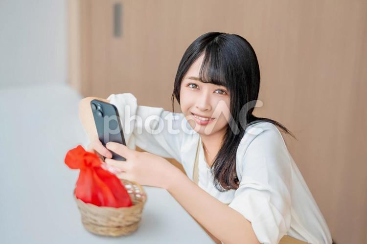 写真を撮りながら笑顔で微笑む女性 バレンタイン,バレンタインデー,チョコの写真素材