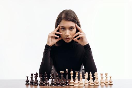 チェスの駒とカメラを見ている女性 チェスの駒とカメラを見ている女性の写真