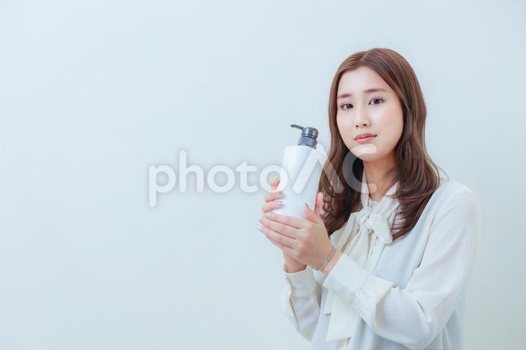 白色のシャンプーを持ったカメラ目線の女性 女性,日本人,若いの写真素材
