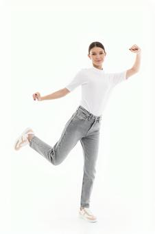 片足をあげポーズするTシャツ女性 片足をあげポーズするTシャツ女性の写真
