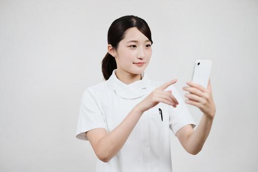 A woman in a white coat operating a smartphone A woman in a white coat operating a smartphone