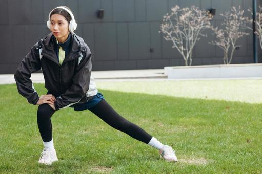 芝生で準備運動する女性 芝生で準備運動する女性の写真