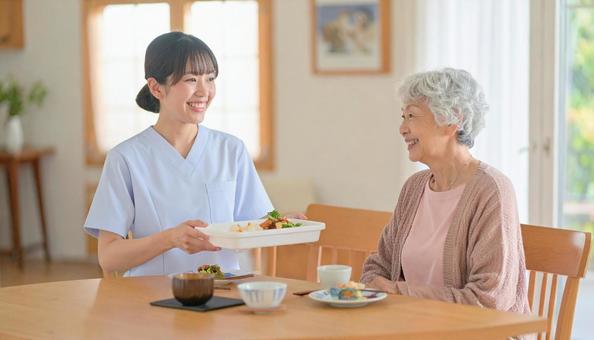 笑顔で食事を運ぶ女性介護士と高齢女性 笑顔で食事を運ぶ女性介護士と高齢女性の写真