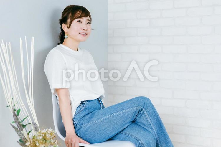 椅子に座って足を組むデニム姿の日本人女性 女性,デニム,足を組むの写真素材