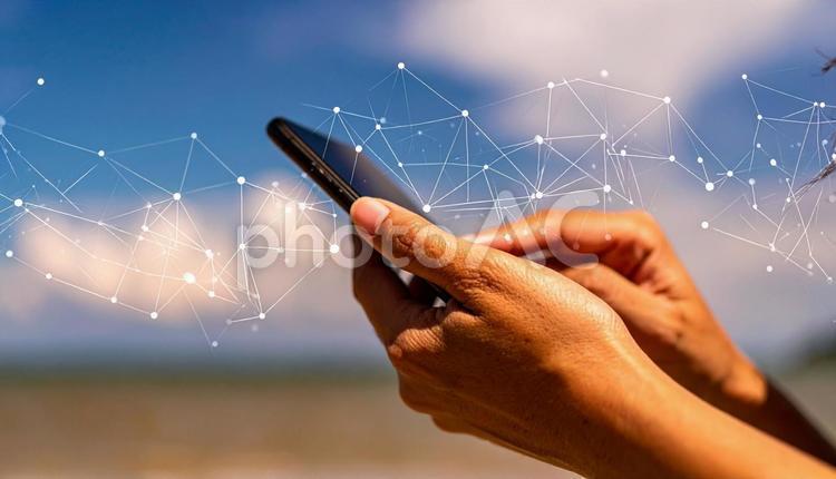 スマートフォンを操作する手　青空背景 スマートフォン,メール,ラインの写真素材