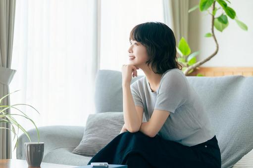 リビングのソファに座る笑顔の女性 リビングのソファに座る笑顔の女性の写真