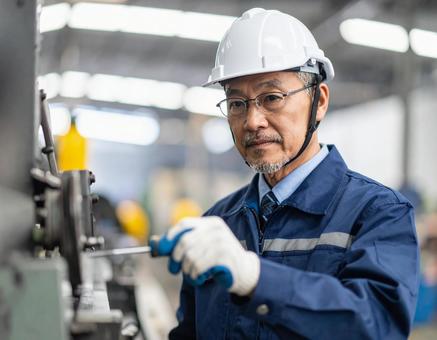 工場で機械を組み立てるベテラン作業員 工場で機械を組み立てるベテラン作業員の写真