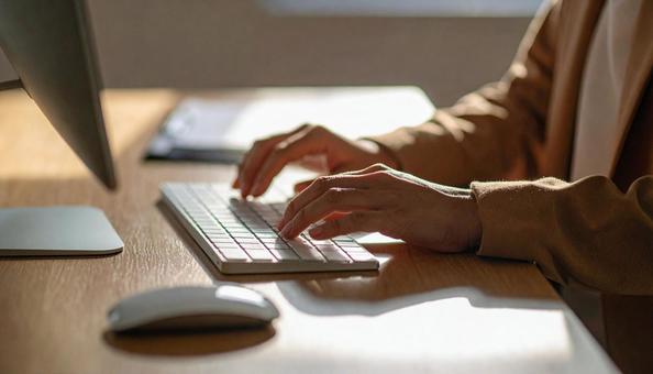 パソコンに両手で入力するデスクワーク パソコンに両手で入力するデスクワークの写真