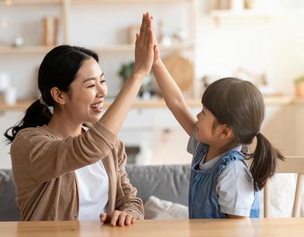 家庭でハイタッチするお母さんと子供 家庭でハイタッチするお母さんと子供の写真