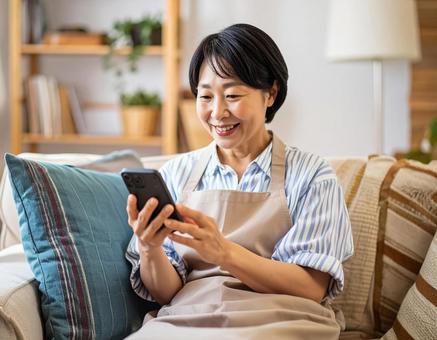 自宅でスマホを操作する女性 自宅でスマホを操作する女性の写真