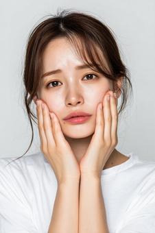 頬に手を当てる20代日本人女性 頬に手を当てる20代日本人女性の写真