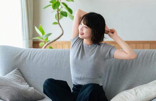ソファに座ってストレッチをする女性 ソファに座ってストレッチをする女性の写真