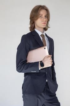 ノートパソコンを抱えるカメラ目線のスーツの男性 男性,外国人,欧米人の写真素材