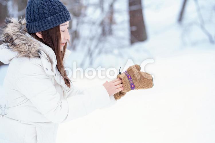 雪の中で手袋をする女性（冬・笑顔） 冬,手袋,雪の写真素材