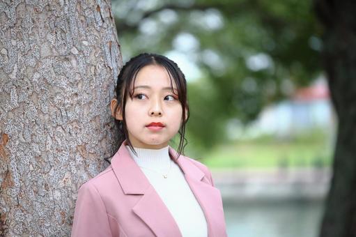 公園の樹木にもたれて遠くを見る女性 女性,20代,公園の写真素材