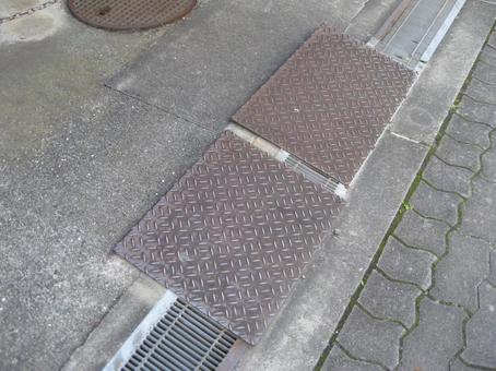 排水溝の蓋の上に置かれた金属プレート 段差,解消,プレートの写真素材