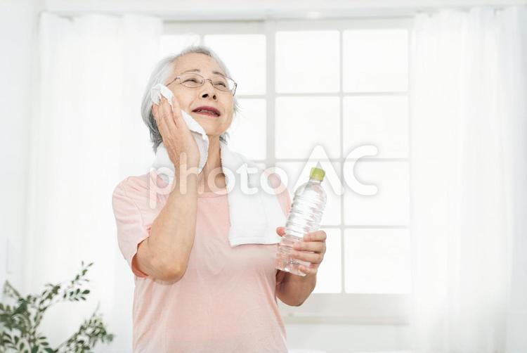 家でトレーニングする女性（水を飲む・笑顔） 高齢者,運動,汗の写真素材
