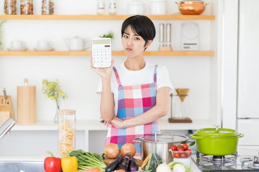 電卓を持って悩む主婦。 電卓を持って悩む主婦。の写真