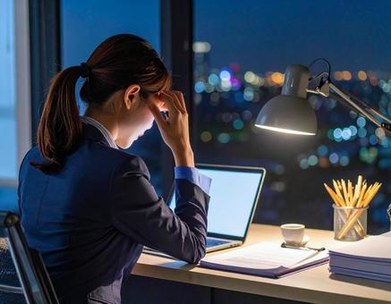残業が終わらず頭を抱える女性 残業が終わらず頭を抱える女性の写真