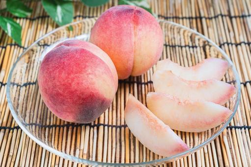 Cut peaches arranged on a bamboo blind and glass plate, JPG