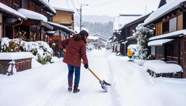 大雪が降った日の翌日の朝に雪かきする女性 大雪が降った日の翌日の朝に雪かきする女性の写真