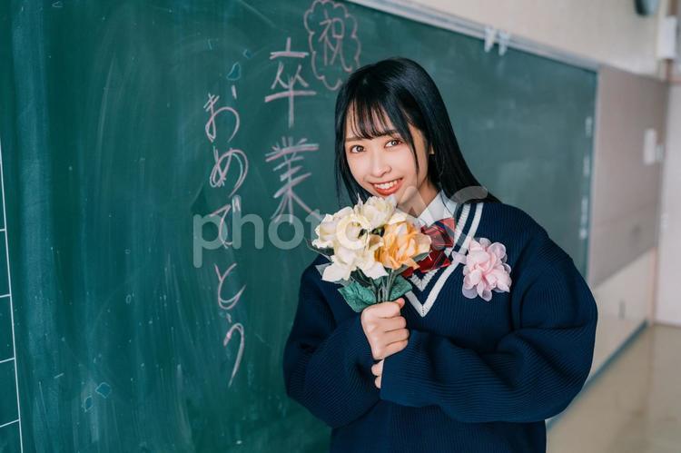 花束を持って笑顔で見つめる女の子の卒業生 女性,女子高,高校生の写真素材