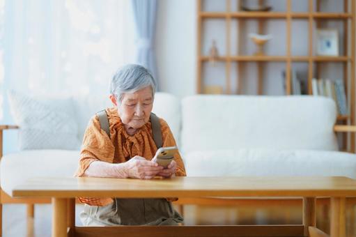真剣な顔でスマートフォンを持つ高齢女性 女性,スマートフォン,持つの写真素材