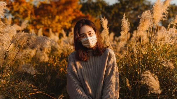秋風に揺れるススキとマスク姿の女性 秋風に揺れるススキとマスク姿の女性の写真