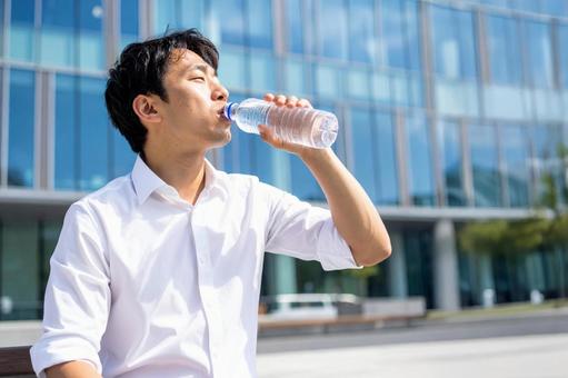 水を飲んで休憩するビジネスマンの写真
