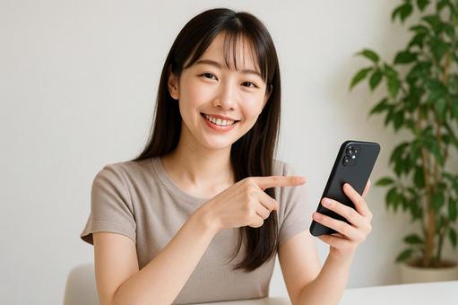 スマホ画面を指差す女性 スマホ画面を指差す女性の写真