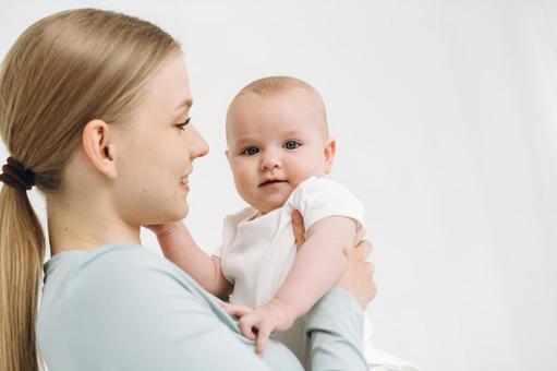 抱っこする横向き女性とカメラ目線の赤ちゃん 抱っこする横向き女性とカメラ目線の赤ちゃん 女性,赤ちゃん,かわいいの写真素材