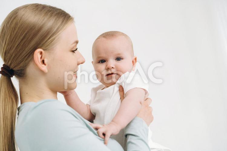 抱っこする横向き女性とカメラ目線の赤ちゃん 女性,赤ちゃん,かわいいの写真素材
