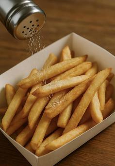 揚げたてのポテトに塩を振る瞬間 揚げたてのポテトに塩を振る瞬間の写真
