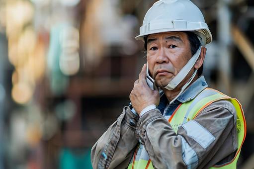 無線・電話で指示を出すベテラン建設監督 無線・電話で指示を出すベテラン建設監督の写真