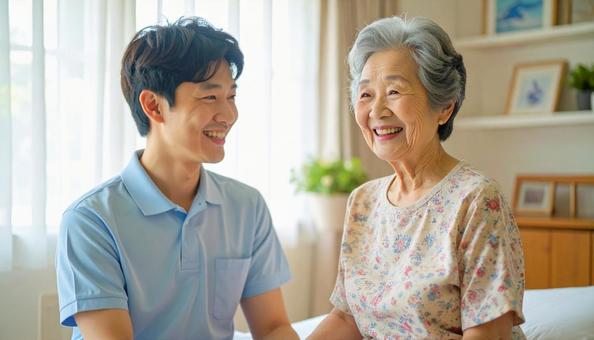 笑顔で話をする男性介護士と高齢女性 笑顔で話をする男性介護士と高齢女性の写真