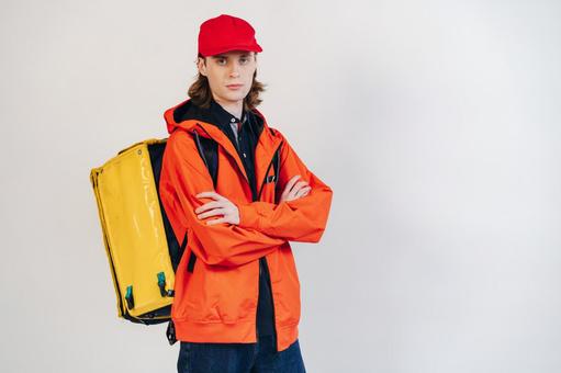 配達バッグを背負って腕組みをするカメラ目線の男性 配達,フードデリバリー,デリバリーの写真素材