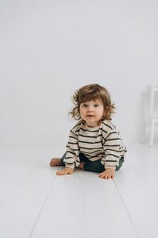 カメラ目線でお座りするボーダー柄の子供 カメラ目線でお座りするボーダー柄の子供 赤ちゃん,かわいい,微笑むの写真素材
