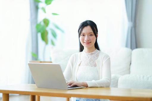 リビングでパソコン中の笑顔の女性 女性,笑顔,笑うの写真素材