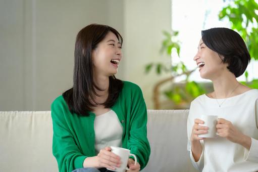 ソファに座って笑い合う日本人女性 ソファに座って笑い合う日本人女性 おしゃべり,リビング,友達の写真素材