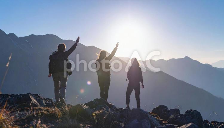 夏山で朝日に向かって手をあげる登山者 夏山,朝日,登山者の写真素材