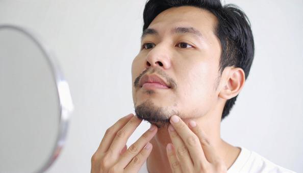 無精髭をさわる男性の手もと 無精髭をさわる男性の手もとの写真