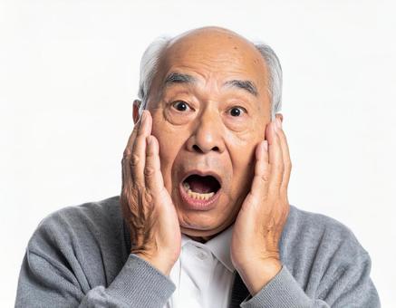 手を頬に当て口を開いて驚く老人 手を頬に当て口を開いて驚く老人の写真