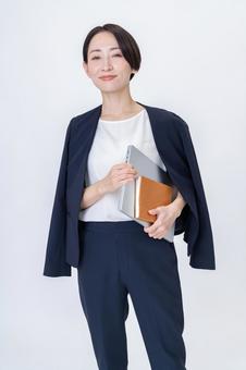 パソコンと手帳を持つ女性 オフィスカジュアル,カジュアルオフィス,かわいいの写真素材