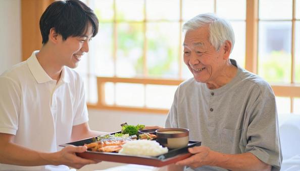 高齢男性と男性介護士の穏やかな食事風景 高齢男性と男性介護士の穏やかな食事風景の写真