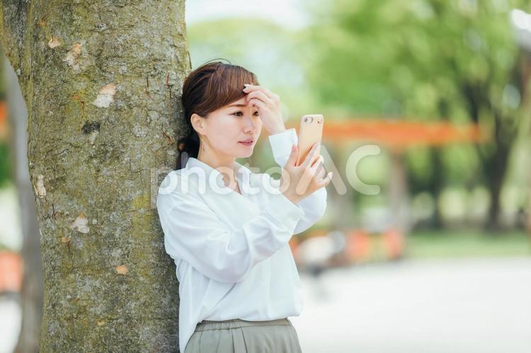 スマホを見るビジネスウーマン 前髪,ビジネスウーマン,直すの写真素材